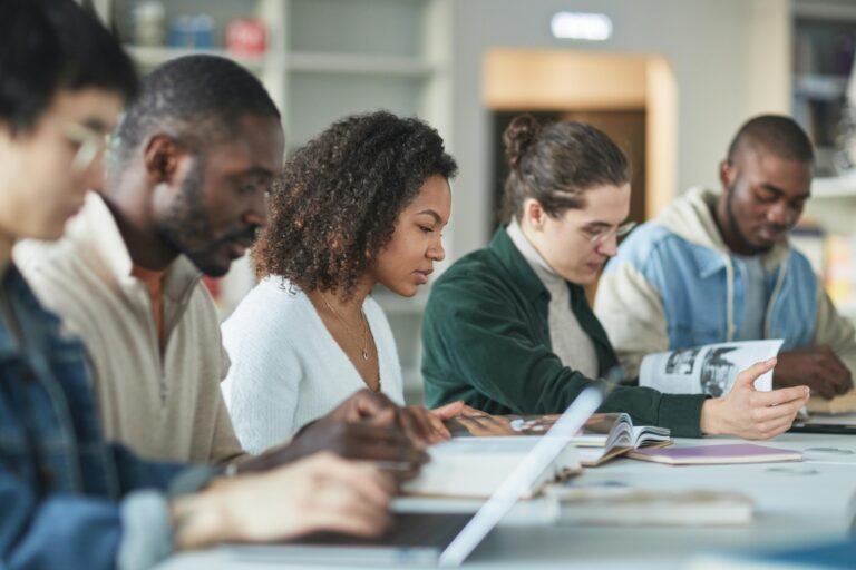 Multiracial group of college students studying together indoors in a library.