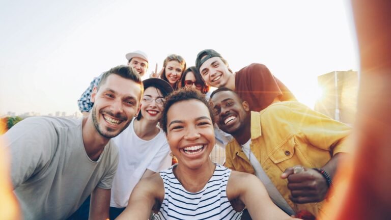 A diverse group of friends taking a joyful selfie outdoors during sunset.
